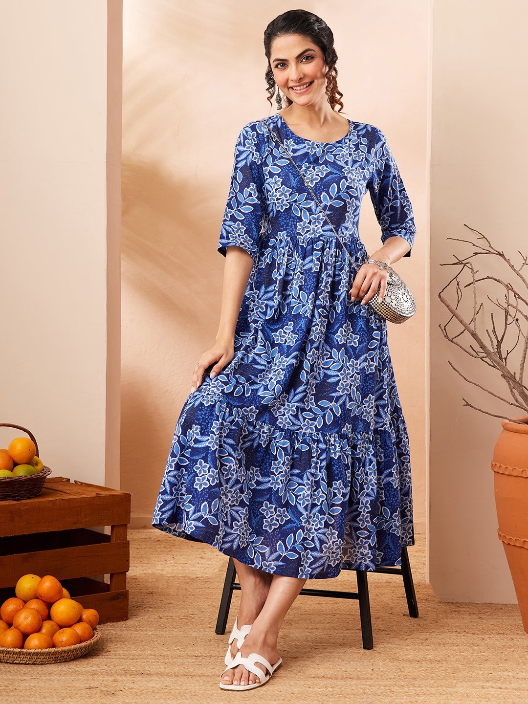 Naanu royal blue floral print midi dress with 3/4 sleeves and tiered skirt. Model wears white sandals.