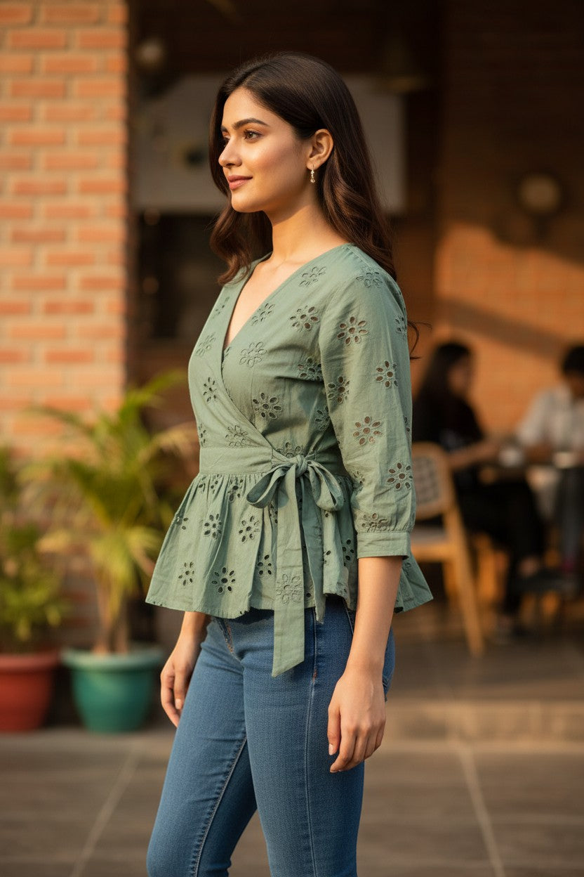 Naanu sage green cotton peplum wrap top with 3/4 sleeves, tie waist, and floral cutwork embroidery.