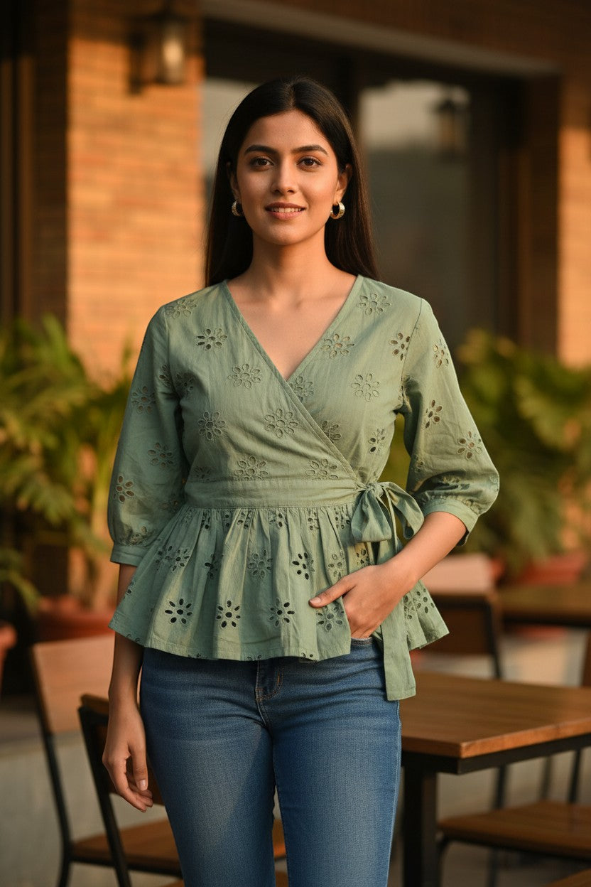 Naanu sage green cotton peplum wrap top with schiffli cutwork embroidery, V-neck, tie waist, and 3/4 sleeves.