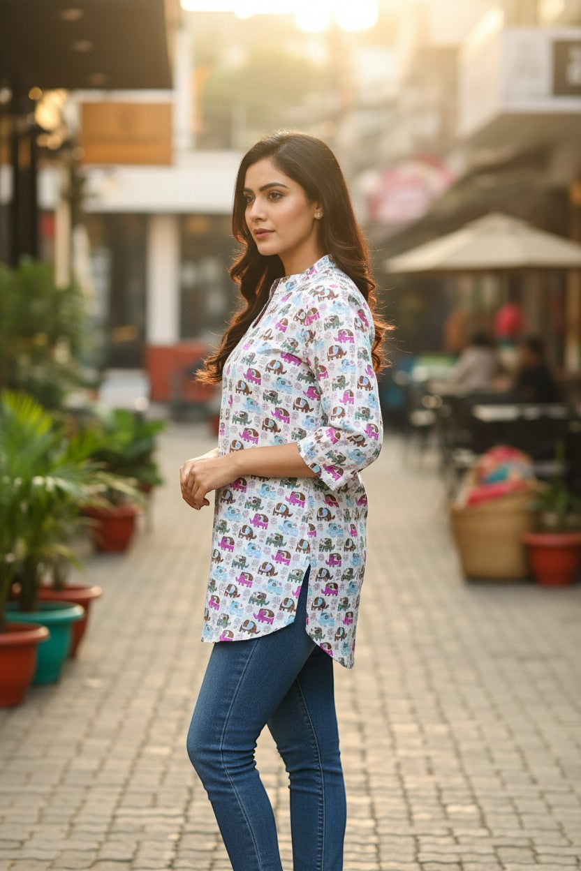 Naanu white short cotton kurti with colorful cartoon elephant print, V-notch neckline, and 3/4 sleeves.