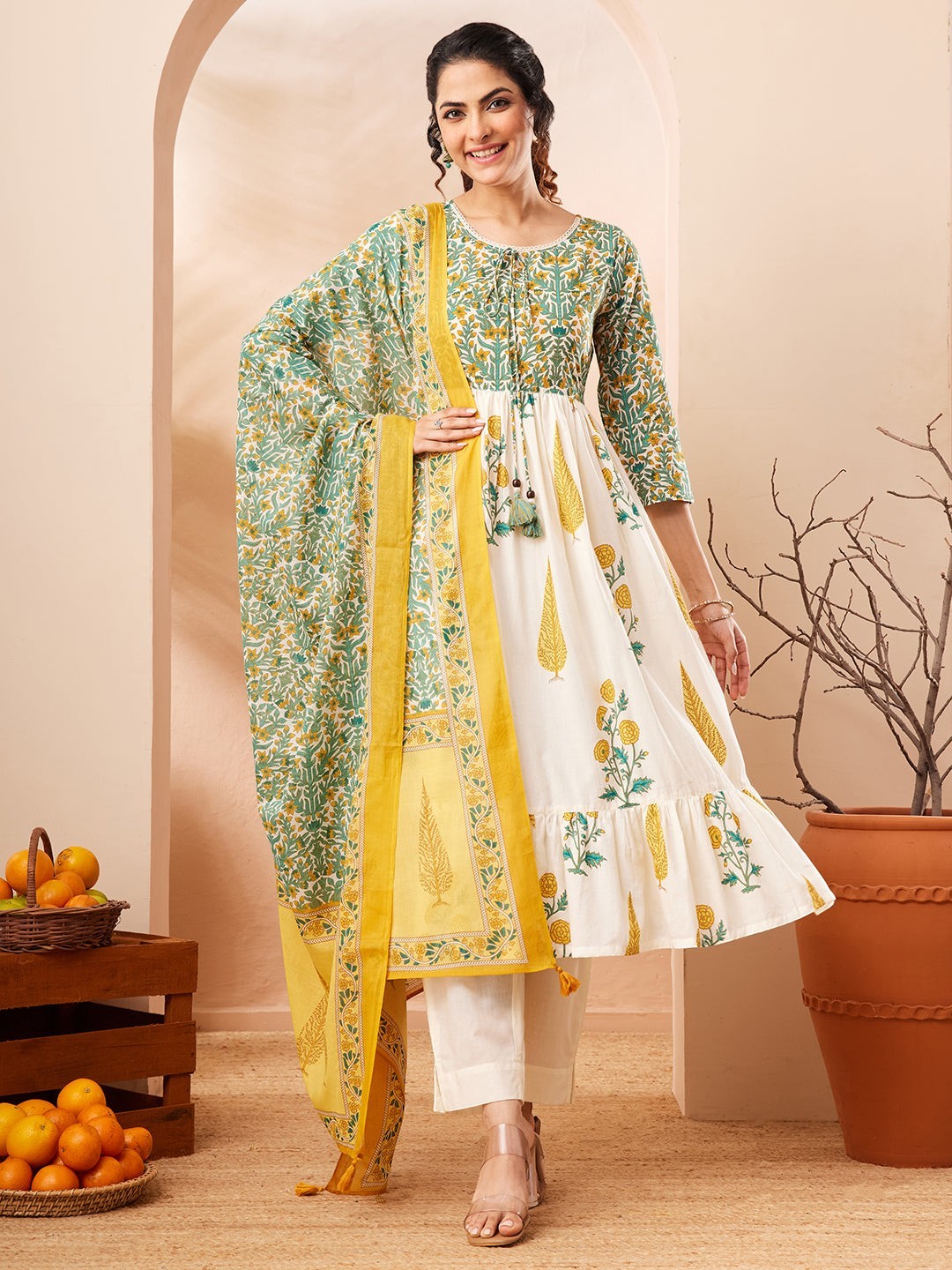 Naanu white and green floral block print Anarkali kurta set with yellow dupatta. Cotton, 3/4 sleeves, tiered ruffle hem.