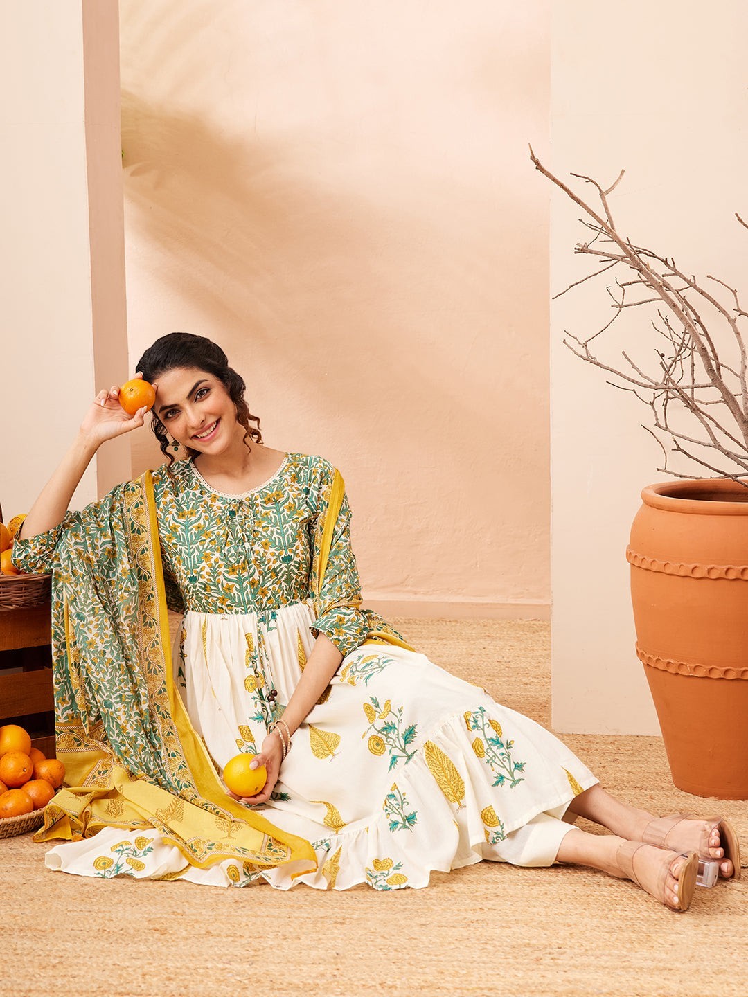 Naanu white and green floral block print Anarkali kurta set with yellow dupatta and tiered ruffle hem. Model wears 3/4 sleeves and round neck.