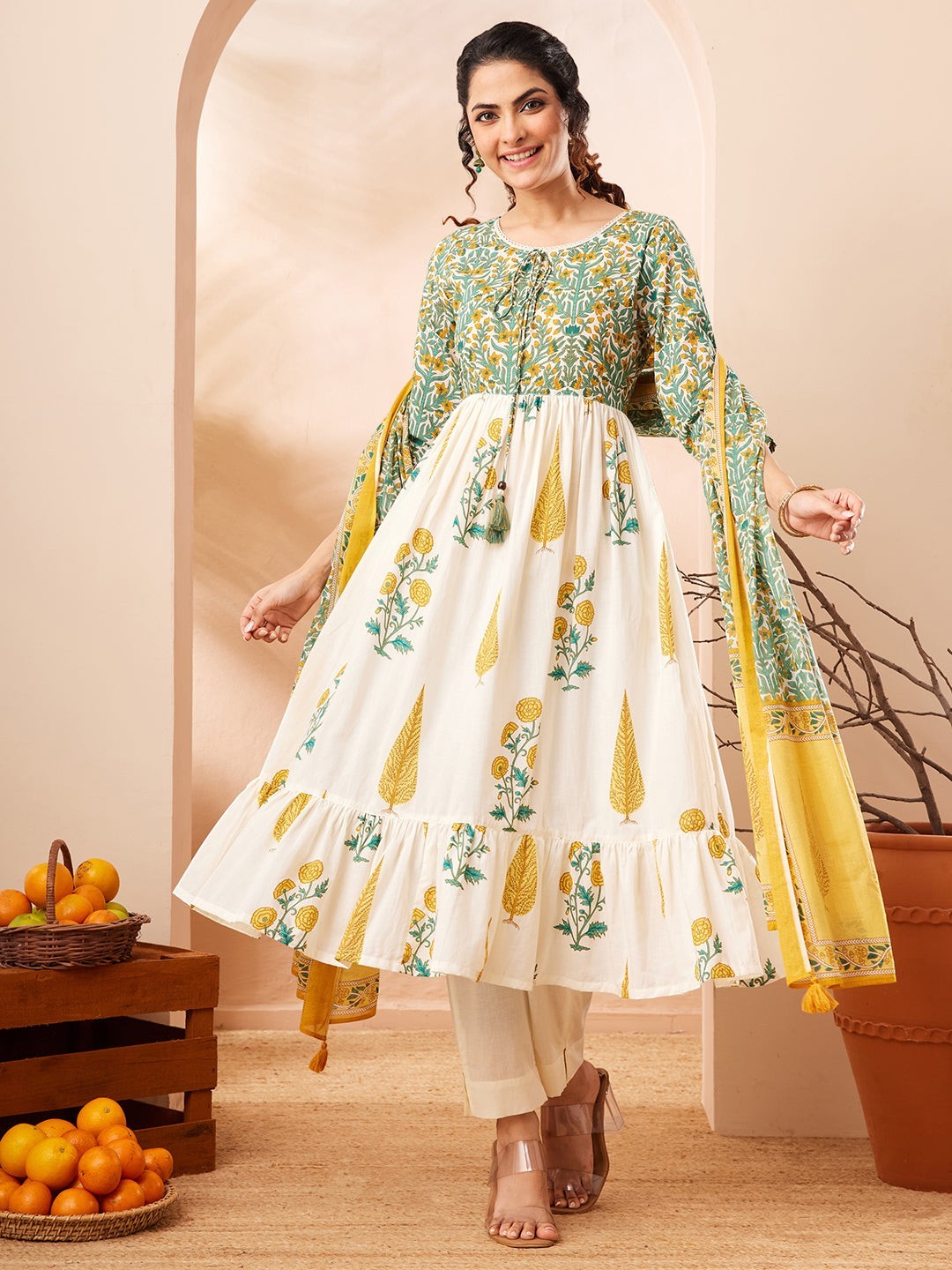 Naanu white and green floral block print Anarkali kurta set with yellow dupatta, featuring a tiered ruffle hem and 3/4 sleeves.