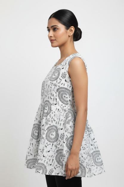 Naanu white cotton short kurta with black Warli tribal print, round neck, sleeveless, and flared peplum silhouette.