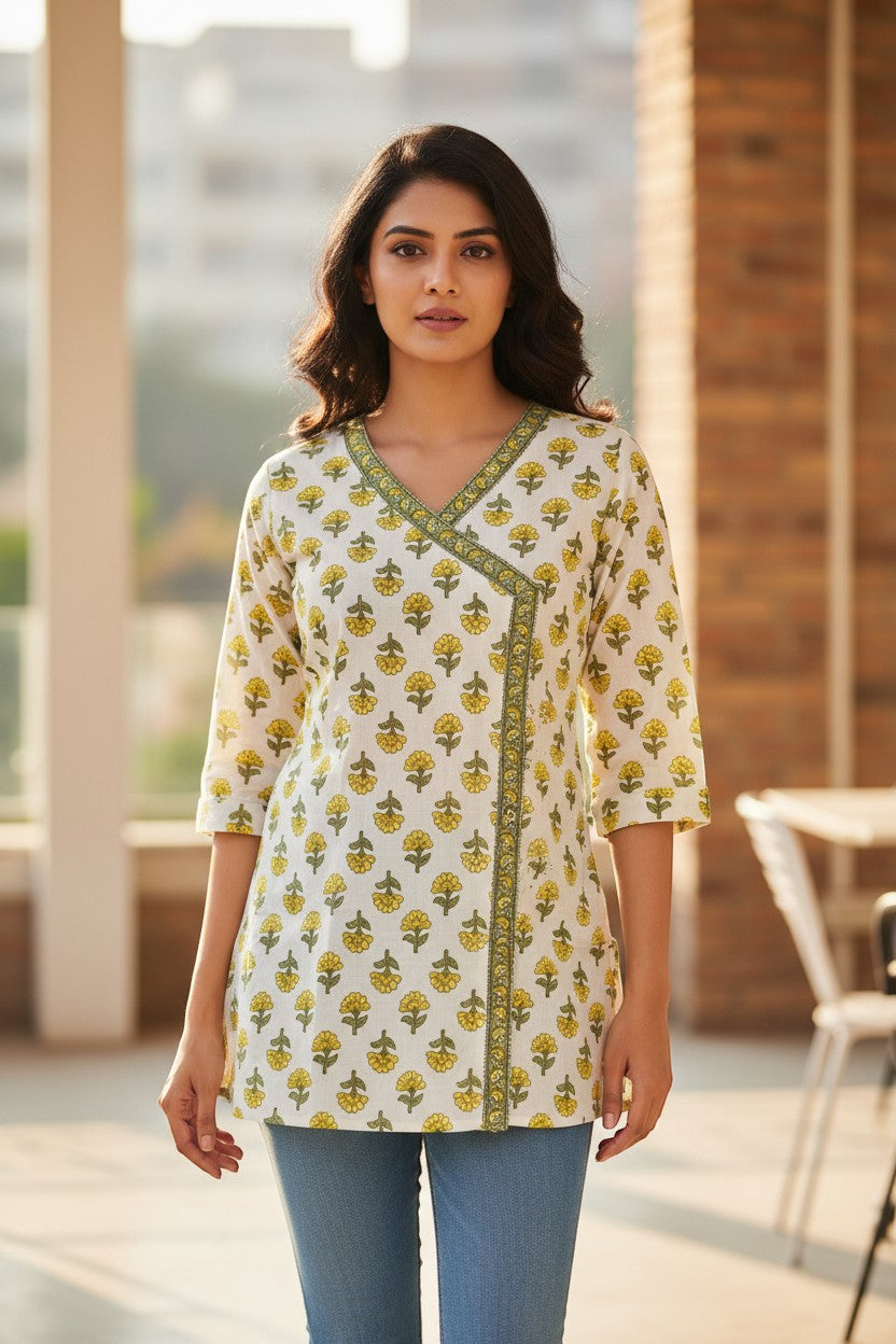 Naanu white cotton kurti with yellow marigold print, V-neck, 3/4 sleeves, and angrakha wrap detail.