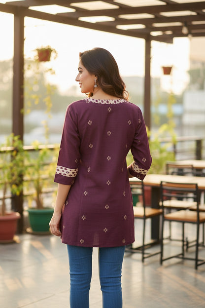Naanu wine purple cotton kurti with geometric motifs and ikat border trim on neckline and sleeves.