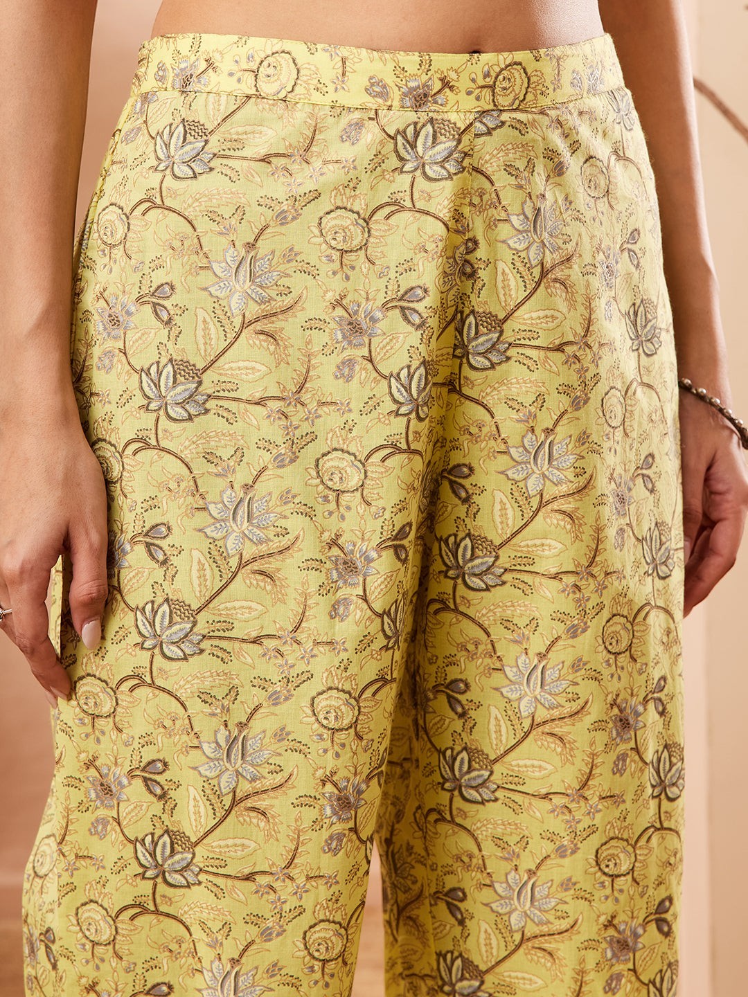 Naanu yellow lotus print sleeveless A-line kurta with V-neck and side pockets, paired with matching wide-leg palazzo pants.
